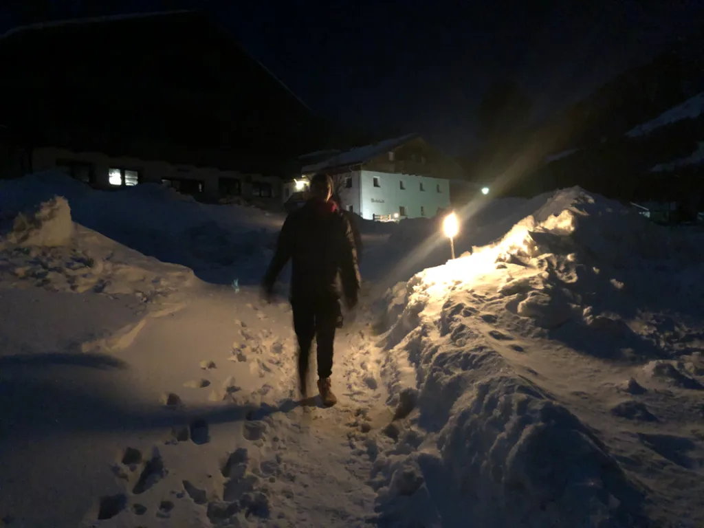 Person geht bei Nacht mit Fackel den Hang hinauf.